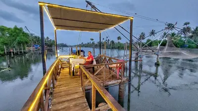 a person sitting on a boat on the water at Vala House in Cherai Beach
