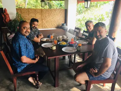 a group of men sitting at a table eating food at Vala House in Cherai Beach