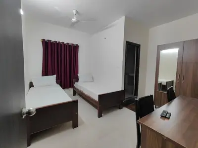 a room with two beds and a desk and a mirror at The Jugglers Rest in Mysore