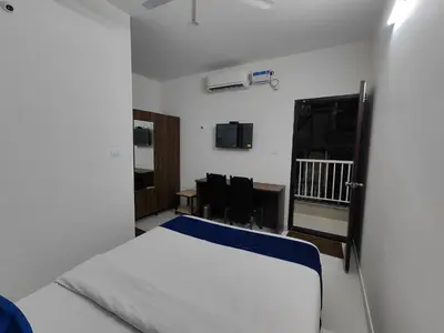 a bedroom with a bed and a desk and chairs at The Jugglers Rest in Mysore
