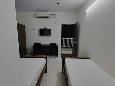 a room with two beds and a table and chairs at The Jugglers Rest in Mysore