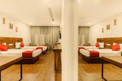 a hotel room with four beds with red pillows at KINGS CALICUT in Kozhikode