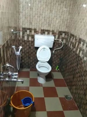a bathroom with a toilet and a checkered floor at SAMZ ESTATE Stay 3BHK in Madikeri