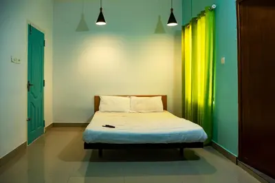 a small bed in a room with a green wall at Ecoville suites in Kozhikode
