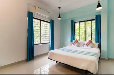 a bedroom with a bed with blue walls and windows at Ecoville suites in Kozhikode