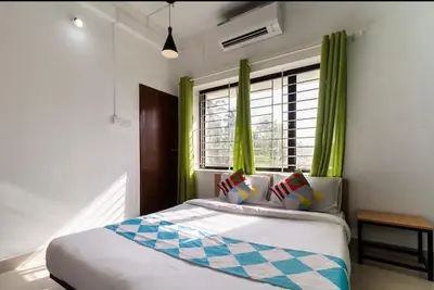 a bedroom with a bed with green curtains and a window at Ecoville suites in Kozhikode