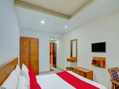 a bedroom with a bed and a tv on the wall at Marhaba Tourist Home in Kozhikode