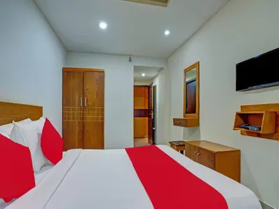 a bedroom with a red and white bed and a television at Marhaba Tourist Home in Kozhikode