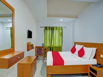 a bedroom with a bed and a desk and a mirror at Marhaba Tourist Home in Kozhikode