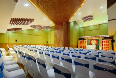 an empty hall with white chairs and a stage at Harivaram Yuga in Guruvāyūr