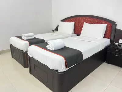two twin beds in a room with white walls at Gee Bee Palace in Angamali