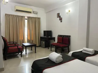 a hotel room with two beds and chairs and a television at Gee Bee Palace in Angamali