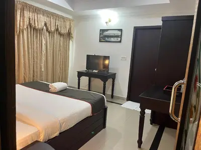 a bedroom with a bed and a desk with a television at Gee Bee Palace in Angamali