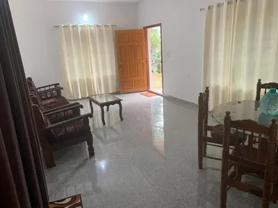 a living room with a table and chairs and a door at Shivalaya Homestay in Madikeri