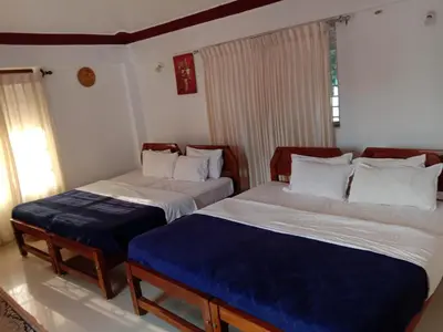 a bedroom with two beds with blue and white sheets at Shivalaya Homestay in Madikeri