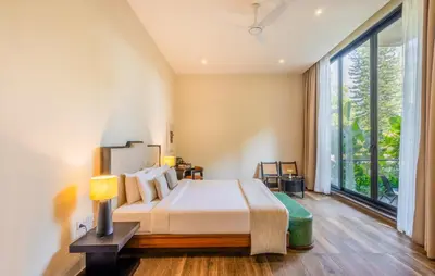 a bedroom with a bed and a large window at Flora Vythiri Resort Wayanad in Vythiri