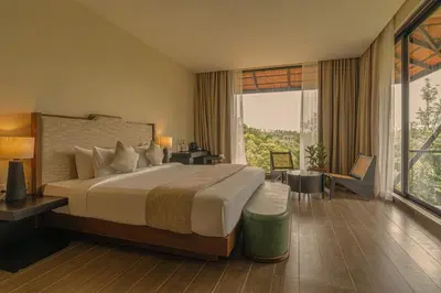 a bedroom with a large bed and a large window at Flora Vythiri Resort Wayanad in Vythiri