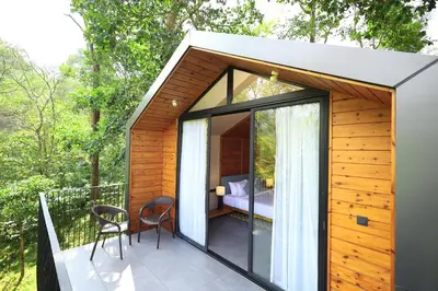 a small house with a balcony with a bedroom at Flora Vythiri Resort Wayanad in Vythiri