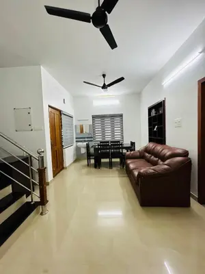 a living room with a couch and a ceiling fan at Saaketh Holiday Home in Kozhikode