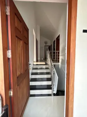 a hallway with stairs and a wooden door at Saaketh Holiday Home in Kozhikode