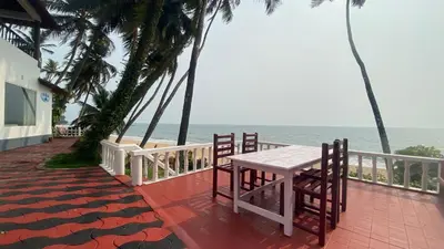 a table and chairs on a balcony overlooking the beach at Willo Stays On the beach Sea view Ocean Hues holiday home in Kannur
