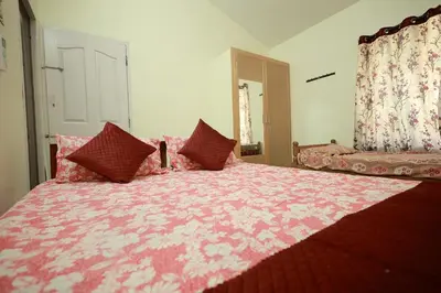 a bedroom with a large pink bed with red pillows at Toms Villa along National highway Thrissur at Nadathara in Trichūr