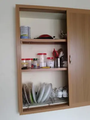a cupboard with plates and other items in it at Toms Villa along National highway Thrissur at Nadathara in Trichūr