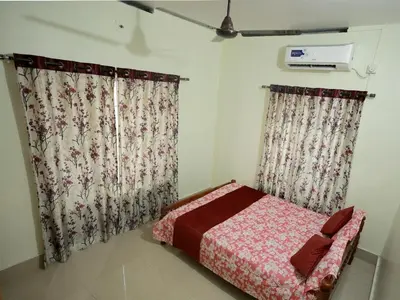 a bedroom with two curtains and a bed in it at Toms Villa along National highway Thrissur at Nadathara in Trichūr