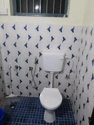 a bathroom with a toilet and blue and white tiles at Toms Villa along National highway Thrissur at Nadathara in Trichūr