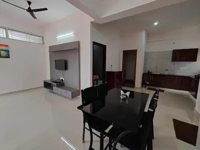 a living room with a black table and chairs at Meer Stay - Premium Service Apartments in Vānivilāsa Puram