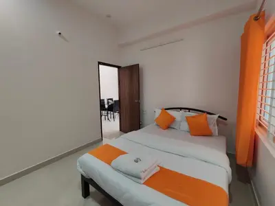 a bedroom with two beds with orange and white pillows at Meer Stay - Premium Service Apartments in Vānivilāsa Puram