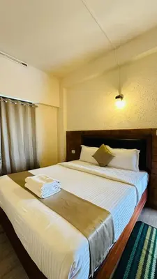 a hotel room with two beds with white sheets at Wild Elephant Resort in Kallar Vattiyar