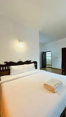 a large white bed with two towels on it at Wild Elephant Resort in Kallar Vattiyar