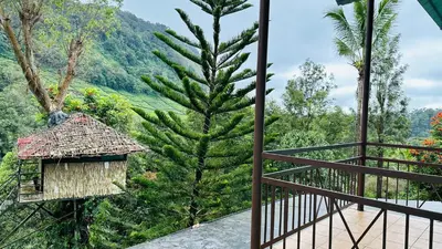 a view from the balcony of a house with a tree at Wild Elephant Resort in Kallar Vattiyar