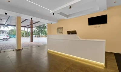 a lobby with a white counter and a tv on the wall at Treebo Grand Vistara Airport Suites in Cochin