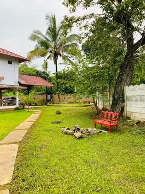 a red bench sitting in the grass next to a house at Greenhouse Homestay in Siddapur