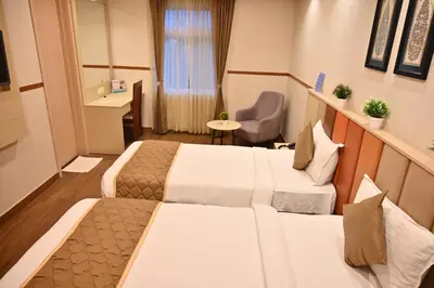 a hotel room with two beds and a chair at Soho Boutique Hotel in Mysore