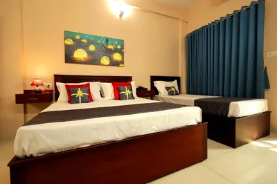 a bedroom with two beds and a blue curtain at Isha Residency in Alwaye