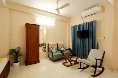 a living room with two chairs and a television at Isha Residency in Alwaye