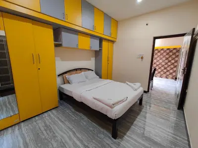 a bedroom with a bed with yellow and blue cabinets at Yellow House in Mysore