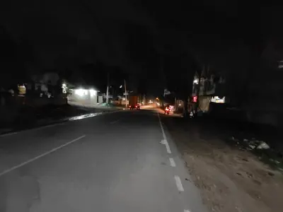 an empty street at night with lights on at Yellow House in Mysore