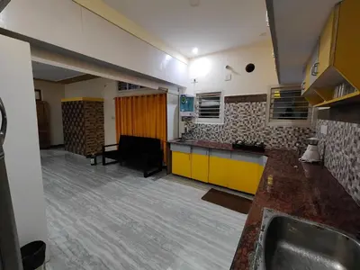 a kitchen with a sink and a couch in a room at Yellow House in Mysore