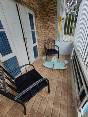 a patio with two chairs and a table on a porch at Yellow House in Mysore