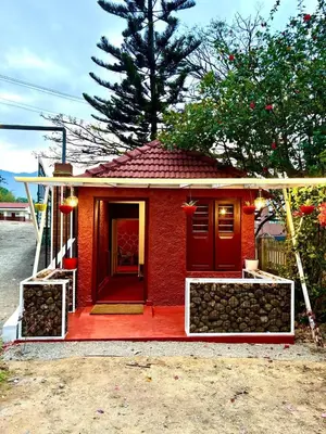 a small red house with a red door at Cure Monastery Family Resort in Marayoor