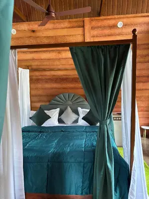 a bedroom with a canopy bed with blue sheets and pillows at Cure Monastery Family Resort in Marayoor