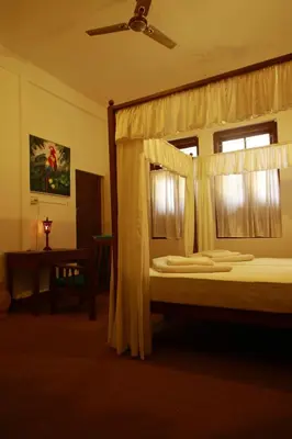 a bedroom with a canopy bed with a window at Cure Monastery Family Resort in Marayoor