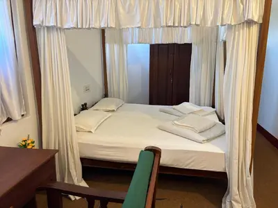 a bedroom with a bed with curtains and a mirror at Cure Monastery Family Resort in Marayoor