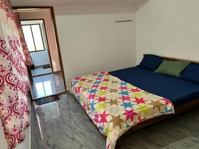 a bedroom with a bed with a quilt on it at Shivalaya Homestay, Madikeri in Siddapur