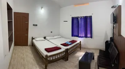 a bedroom with two beds and a window at Dakshinakasi Guest House in Thirunelli