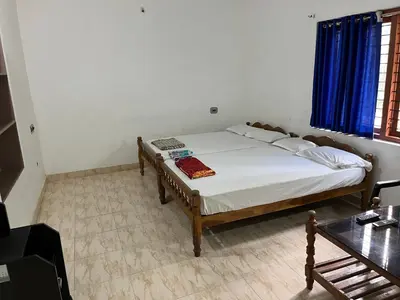 a bedroom with a bed and a table in it at Dakshinakasi Guest House in Thirunelli